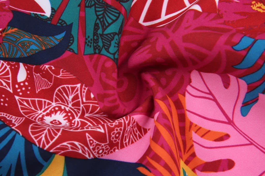 Colourful fabric featuring a vibrant floral design in shades of red, pink, blue, and green, with a logo present.