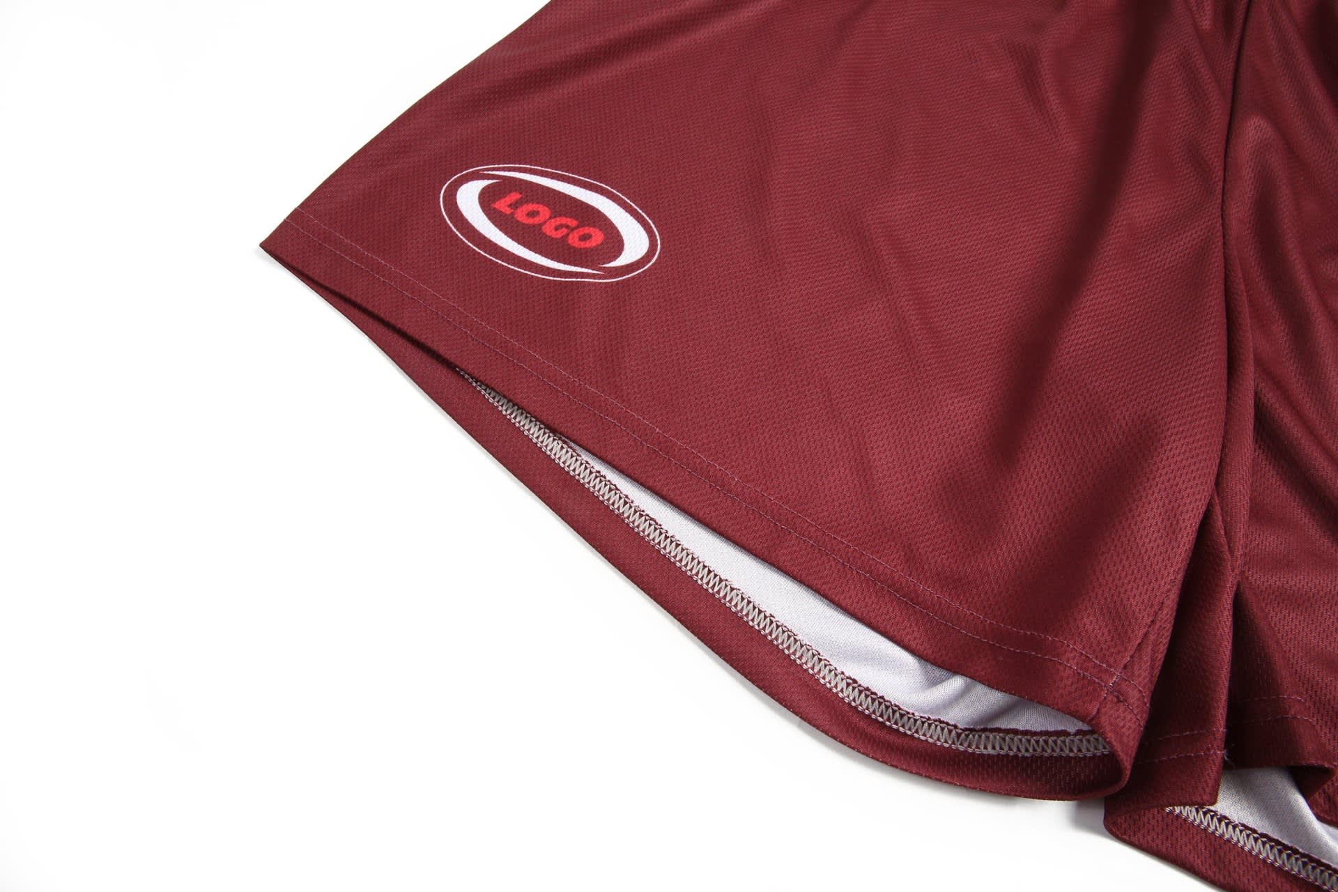 Maroon shorts featuring a logo, with a smooth texture and contrasting inner lining.