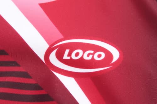 A close-up of a red sports uniform featuring a logo and abstract design patterns.