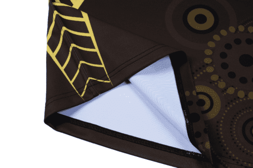 A brown rugby top featuring circular patterns in yellow and black, with a woven detail at the edge and a logo.