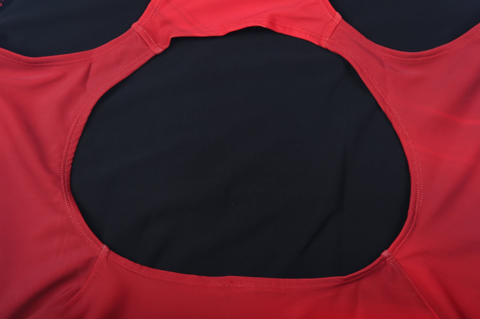 A red women's swimming one-piece with a circular cutout at the back, featuring a logo.