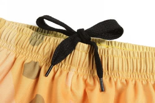 A close-up of an orange sports uniform featuring a black drawstring and a patterned waistband.