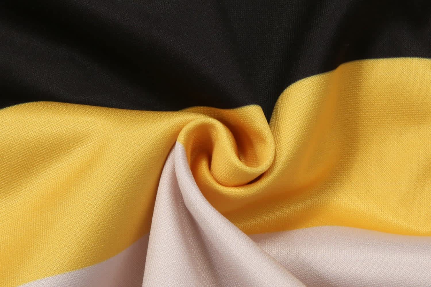 A fabric featuring black, yellow, and cream colours, showcasing a smooth, curled texture.