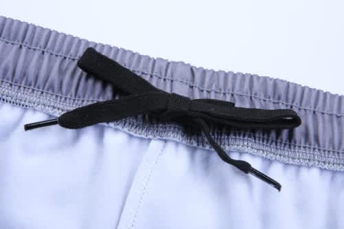 A pair of grey training zip pants featuring a black drawstring at the waist.