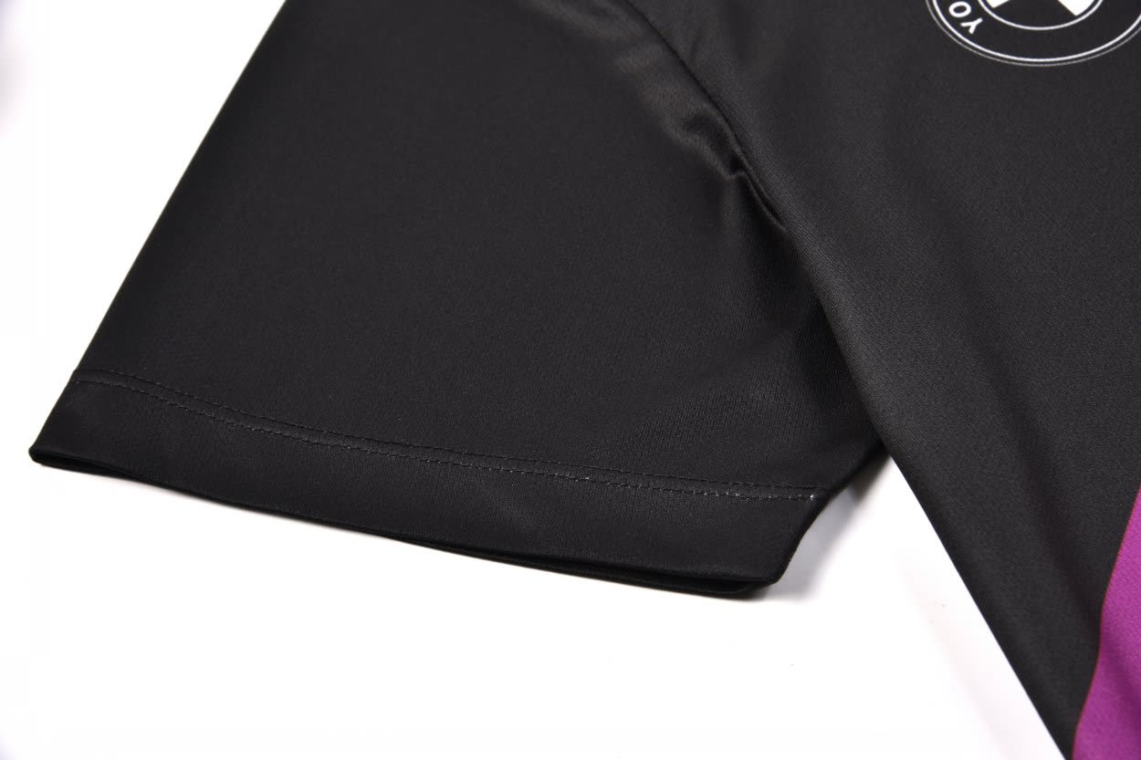 A black football top jersey with a purple accent on the sleeve and a logo.