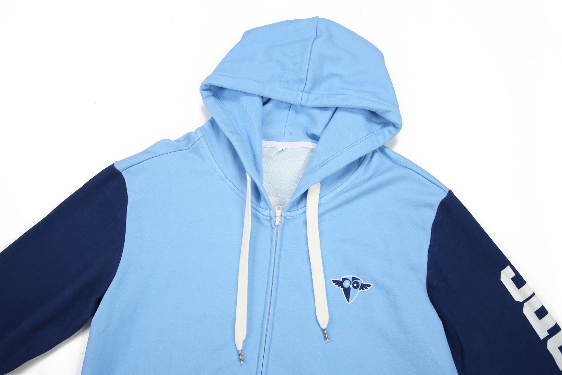 A light blue hoodie with a navy blue sleeve, featuring a logo on the chest and a drawstring hood.