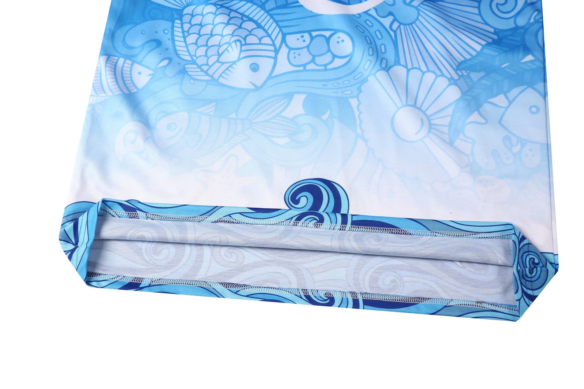 A blue and white fishing team uniform features an intricate ocean-themed design with fish and shells. It has a logo.