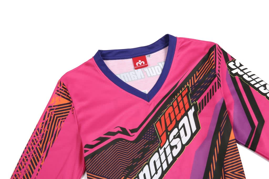 A pink BMX T-shirt featuring a V-neck design and vibrant geometric patterns, with a logo on the collar.