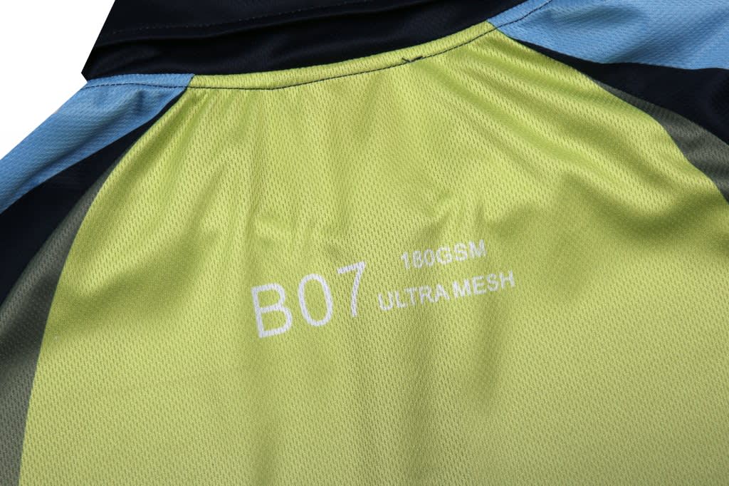 A close-up of a fabric with a light green and dark blue design, featuring texture details and a small logo.