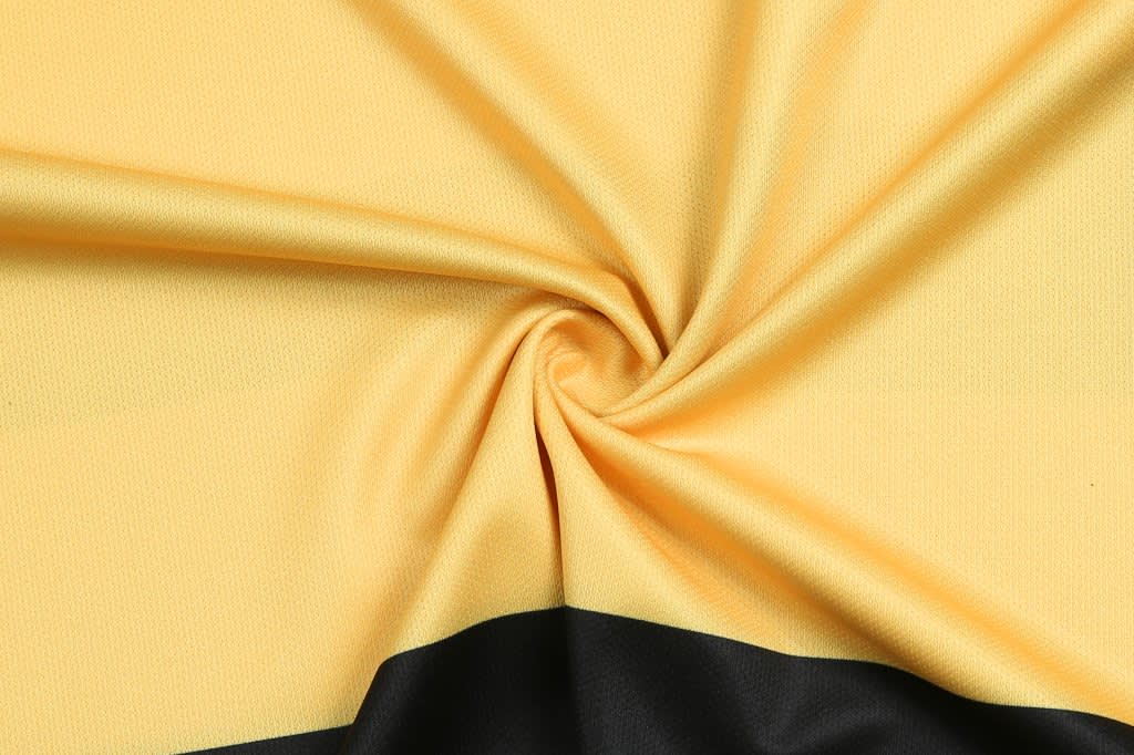 A yellow and black fabric, twisted to showcase its texture and colour, suitable for custom design team t-shirts.