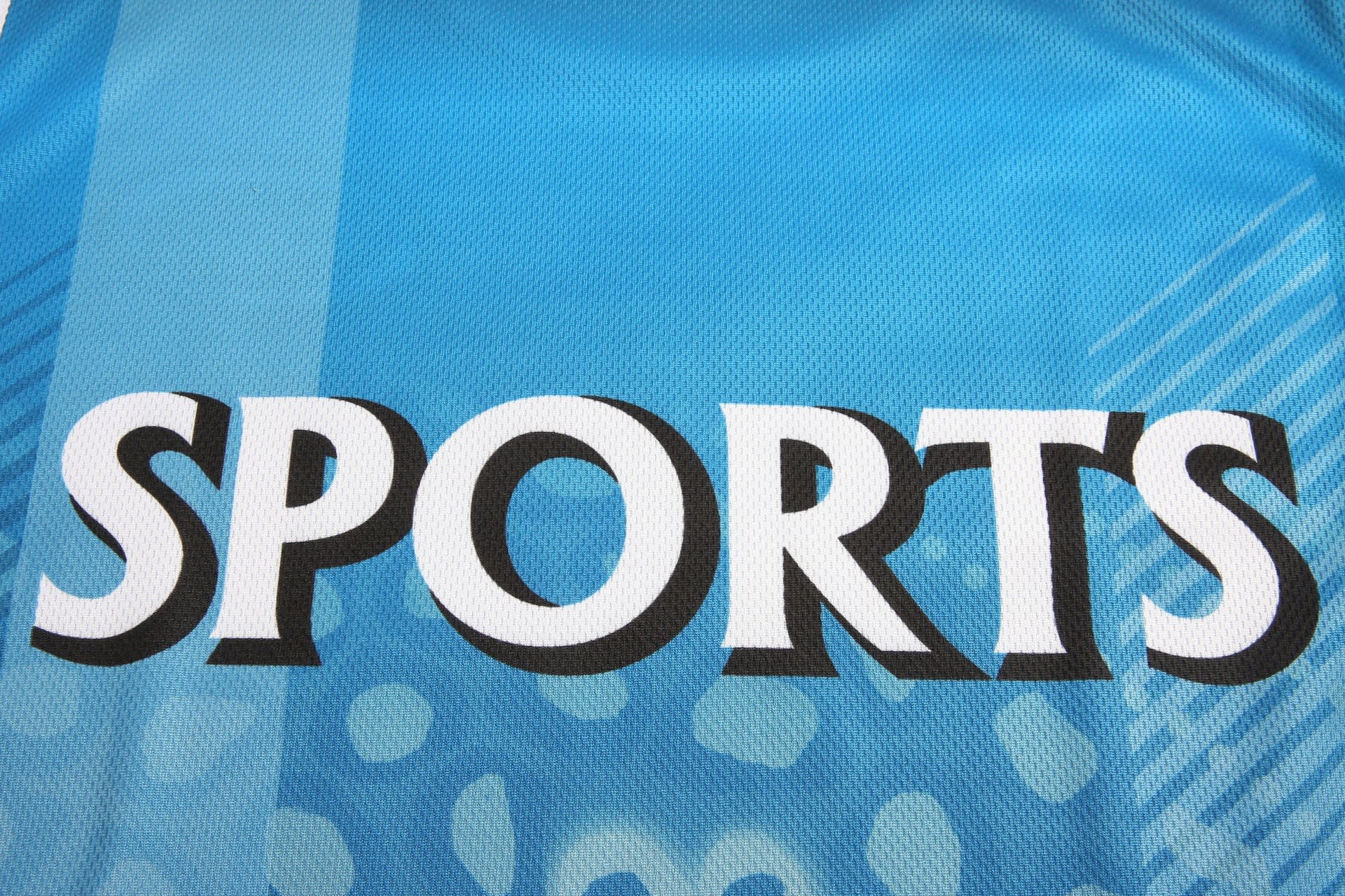 A blue singlet vest with a mesh texture featuring the word "SPORTS" prominently displayed. It includes branding.