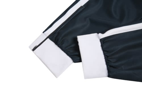 A dark green cricket jersey sleeve featuring white cuffs and a zipper detail. The jersey has a branded logo.