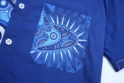 A cotton shirt featuring a blue patterned pocket and a solid blue body, complete with buttons and a logo.