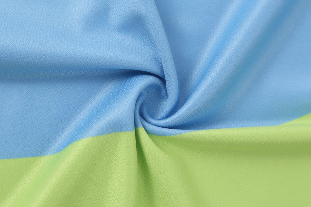 A fabric swatch in light blue and green, featuring a smooth texture and spiral pattern.