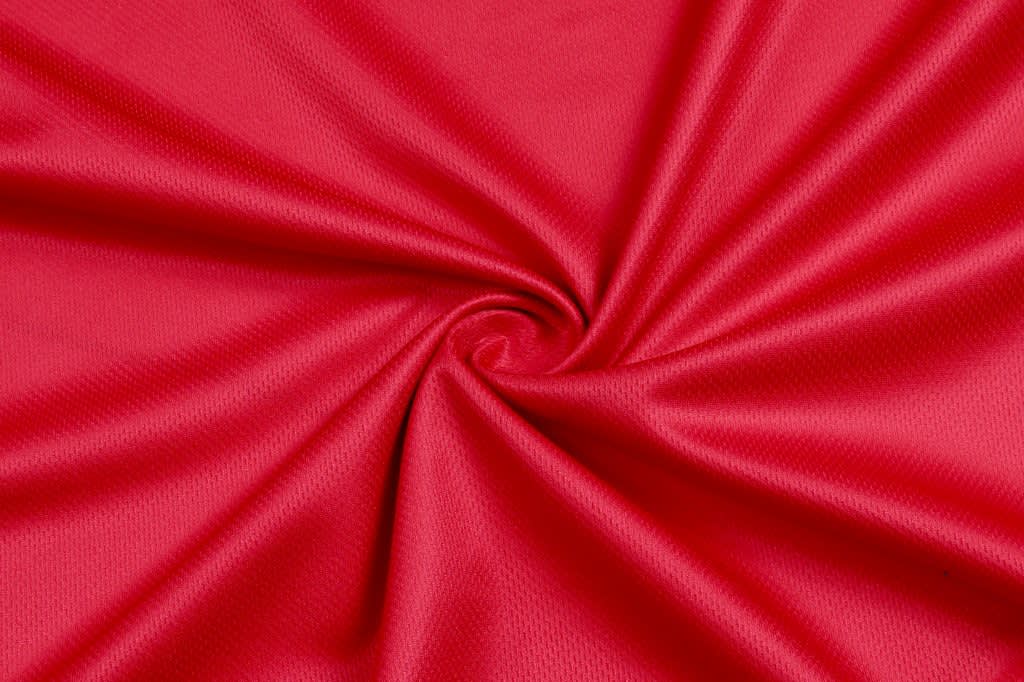 A vibrant red fabric with a smooth texture, arranged in a circular pattern.