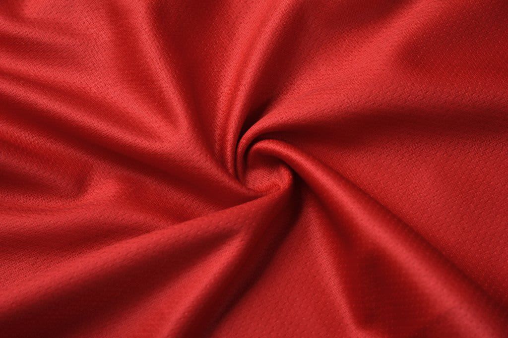 A textured fabric in vibrant red, showcasing a smooth, woven pattern with a slight sheen.