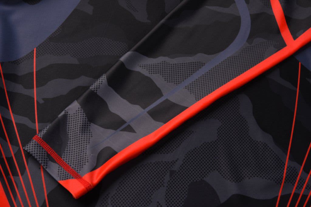 A black and grey camouflage compression tee with red accents and a logo.