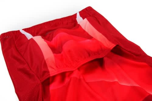 A red cycling uniform featuring breathable fabric with white accents and a logo. The interior showcases a smooth finish.
