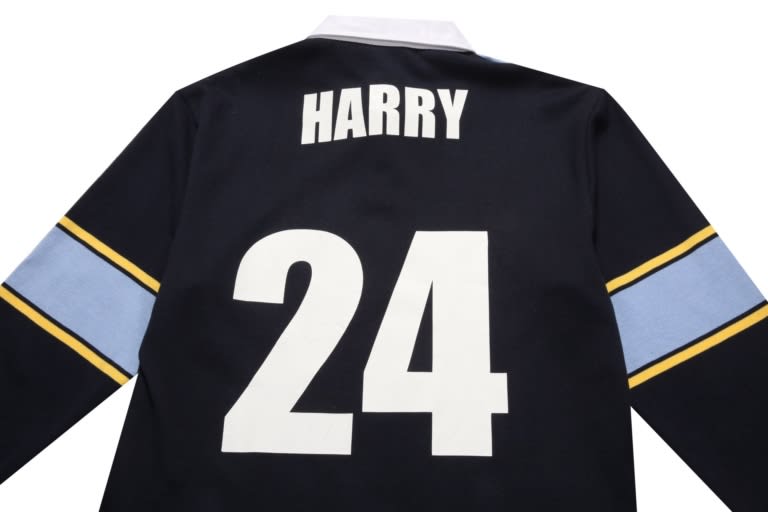 A black sports jumper featuring a white number "24" and a name on the back, with blue and yellow stripes on the sleeves.