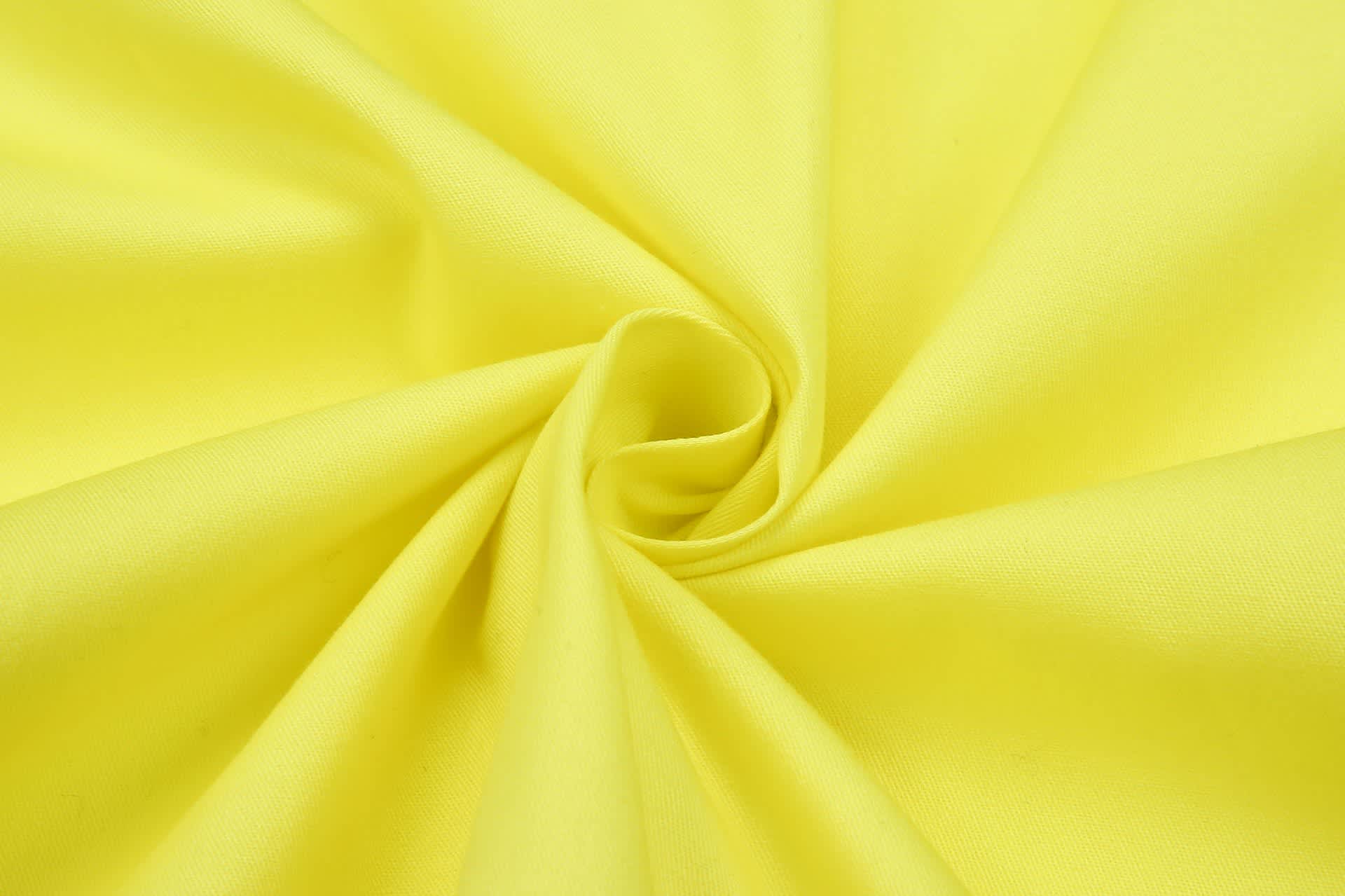 A close-up of bright yellow fabric, showcasing the texture and smoothness of the textile.