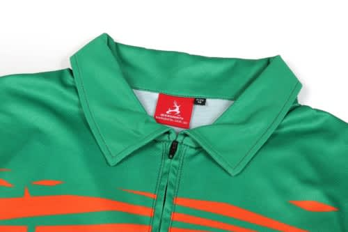 A green quarter zip suit with an orange design and a collar. It features a logo on the label inside.