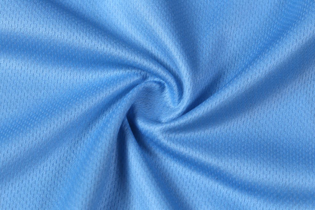 A light blue fabric with a textured, breathable weave, ideal for sportswear. Features a swirling pattern.