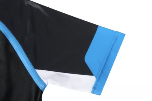 A close-up of a sports uniform sleeve featuring black fabric with blue and white detailing and a logo.