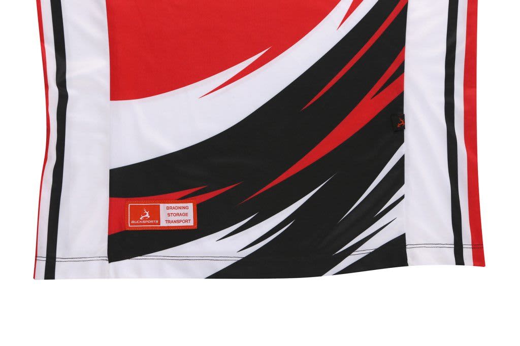A fabric featuring bold red, white, and black patterns with a logo and label indicating the brand.