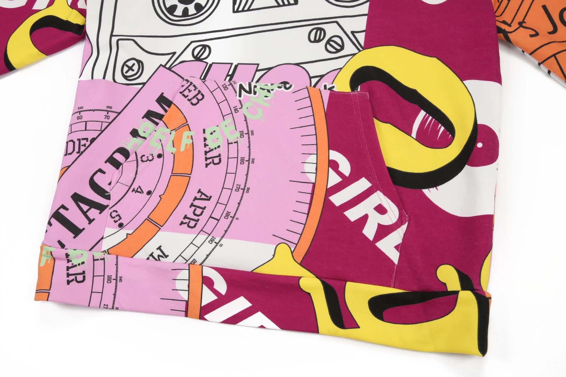 A brightly coloured cotton hoodie featuring bold graphic patterns and a pocket. The design includes pink, yellow, and purple elements.