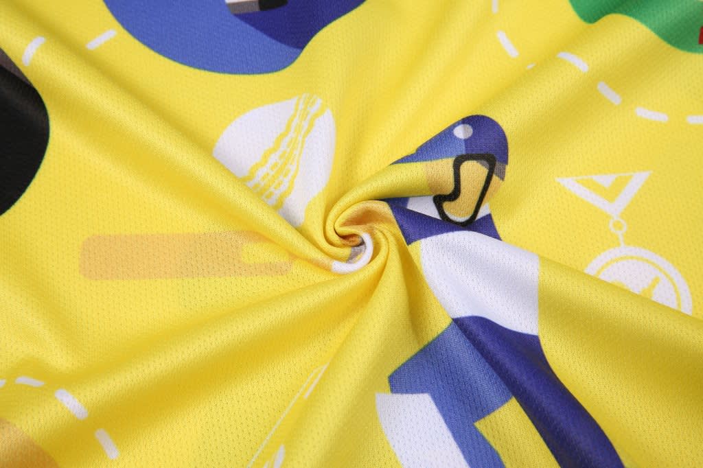 A vibrant yellow fabric featuring a variety of playful designs in blue, black, and white.