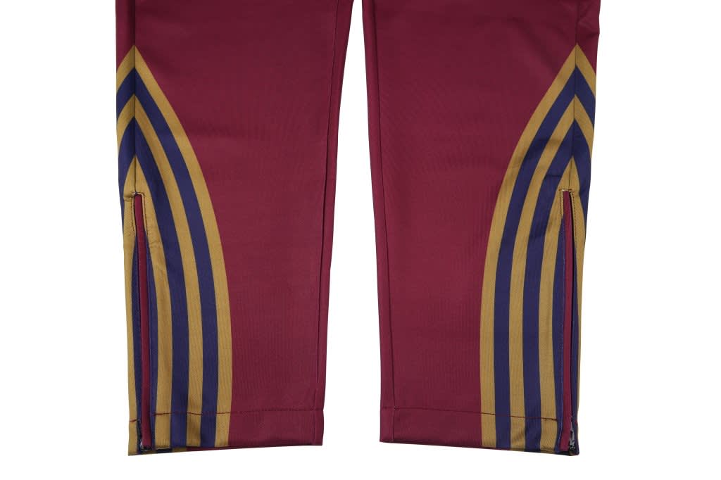 Zipper bottom training pants in maroon, featuring decorative stripes in gold, blue, and red. Includes a small logo.
