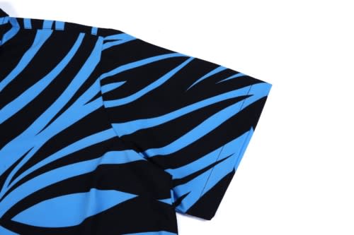 A blue and black patterned shirt featuring a bold zebra stripe design on the sleeve. The shirt has a logo.