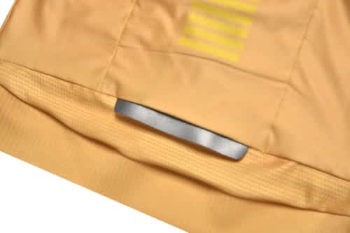 A close-up of a yellow sports jersey featuring mesh detailing and a branding label at the bottom.