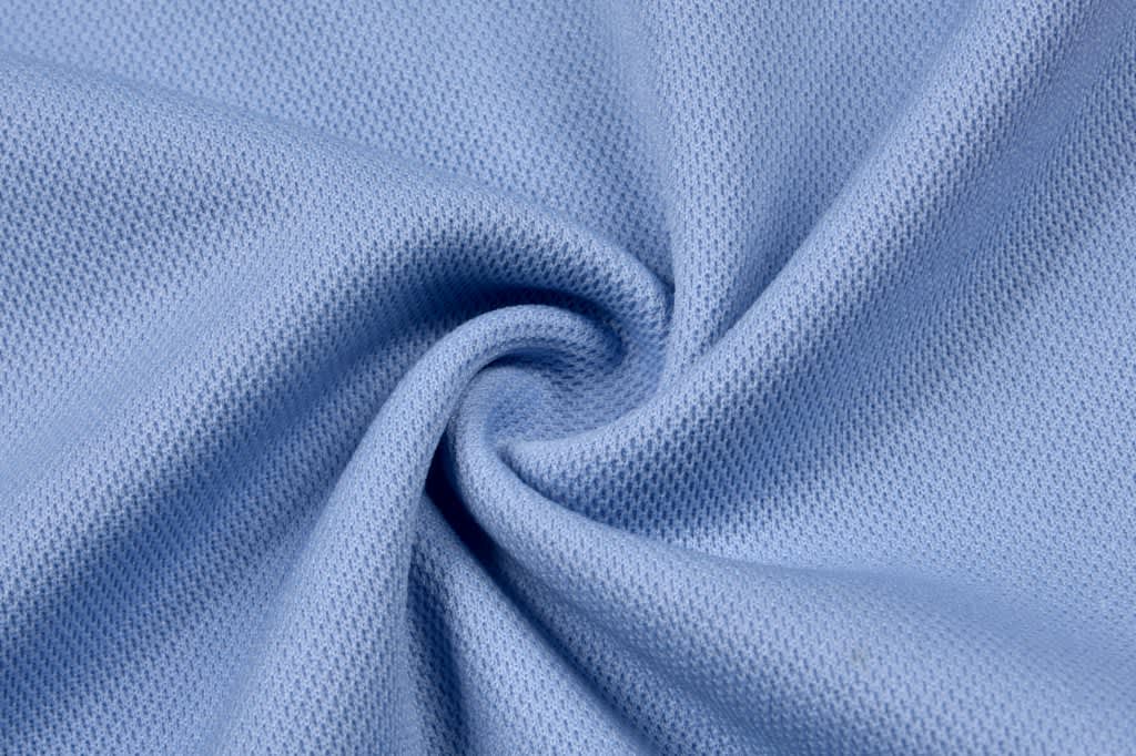 A light blue fabric displaying a smooth, textured pattern, likely for a polo shirt design.
