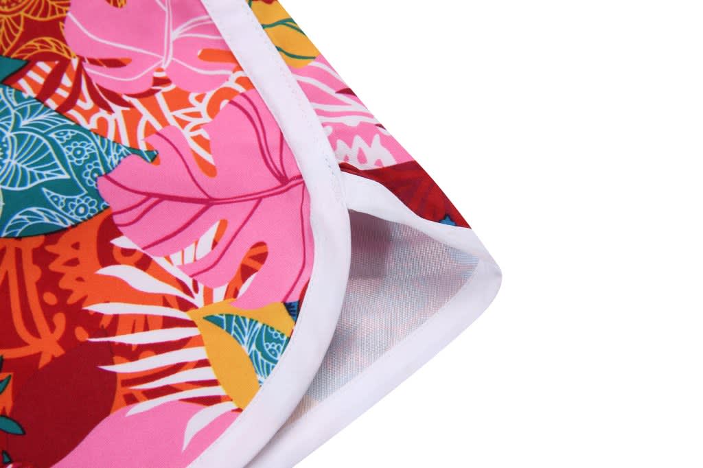 A vibrant pair of women's boardshorts featuring a floral pattern in pink, red, and green with a white trim.