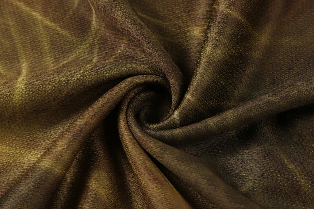 A folded piece of fabric with a rich brown and gold pattern, showcasing a smooth texture. The image has a branding logo.