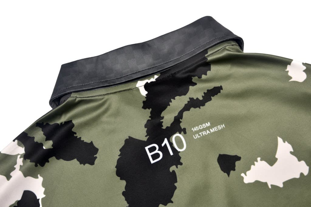 A camouflage polo shirt featuring a mix of green and black patterns, with a black collar and branding on the back.