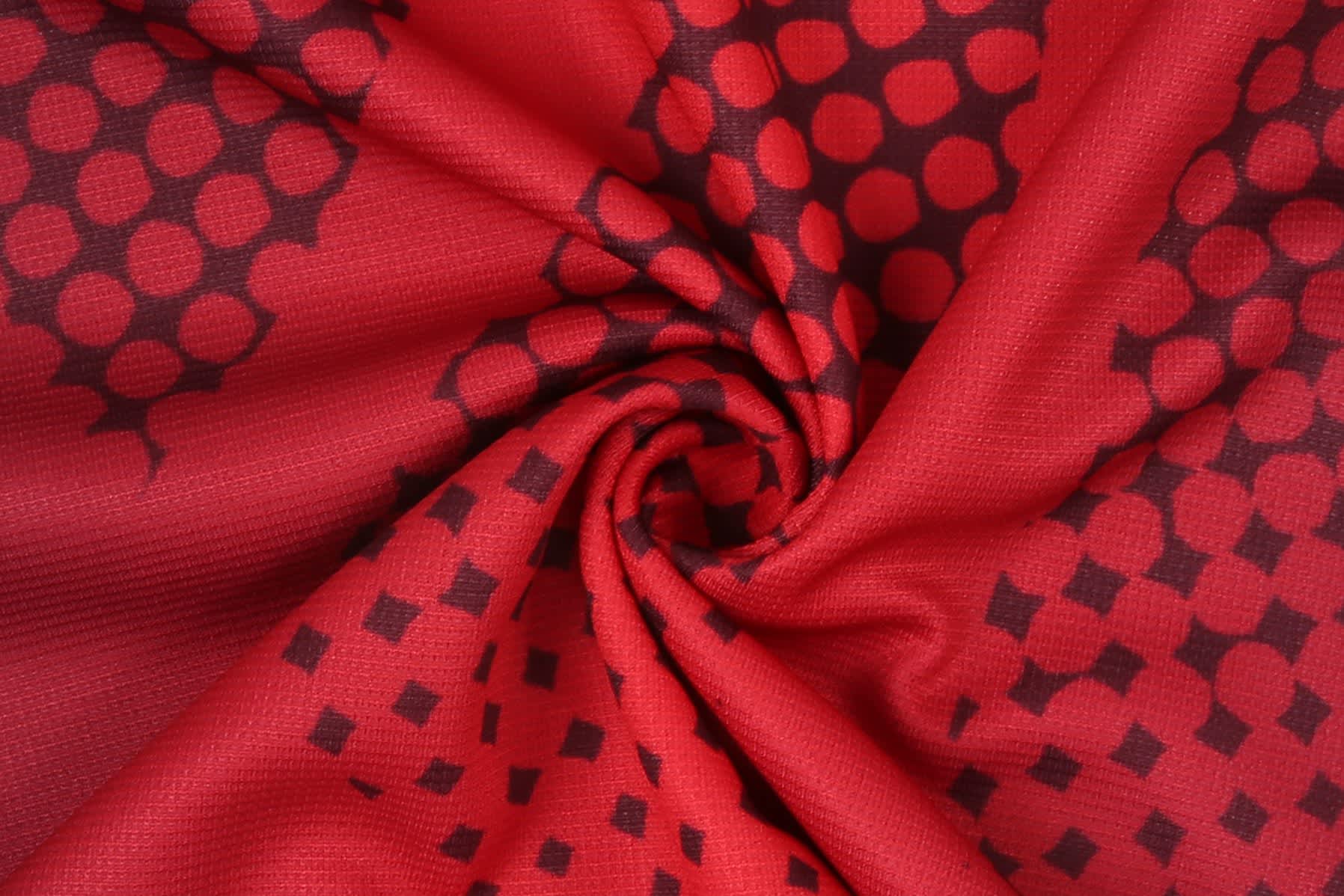 A red fabric with a textured pattern of circles and squares, featuring a smooth, swirling design.
