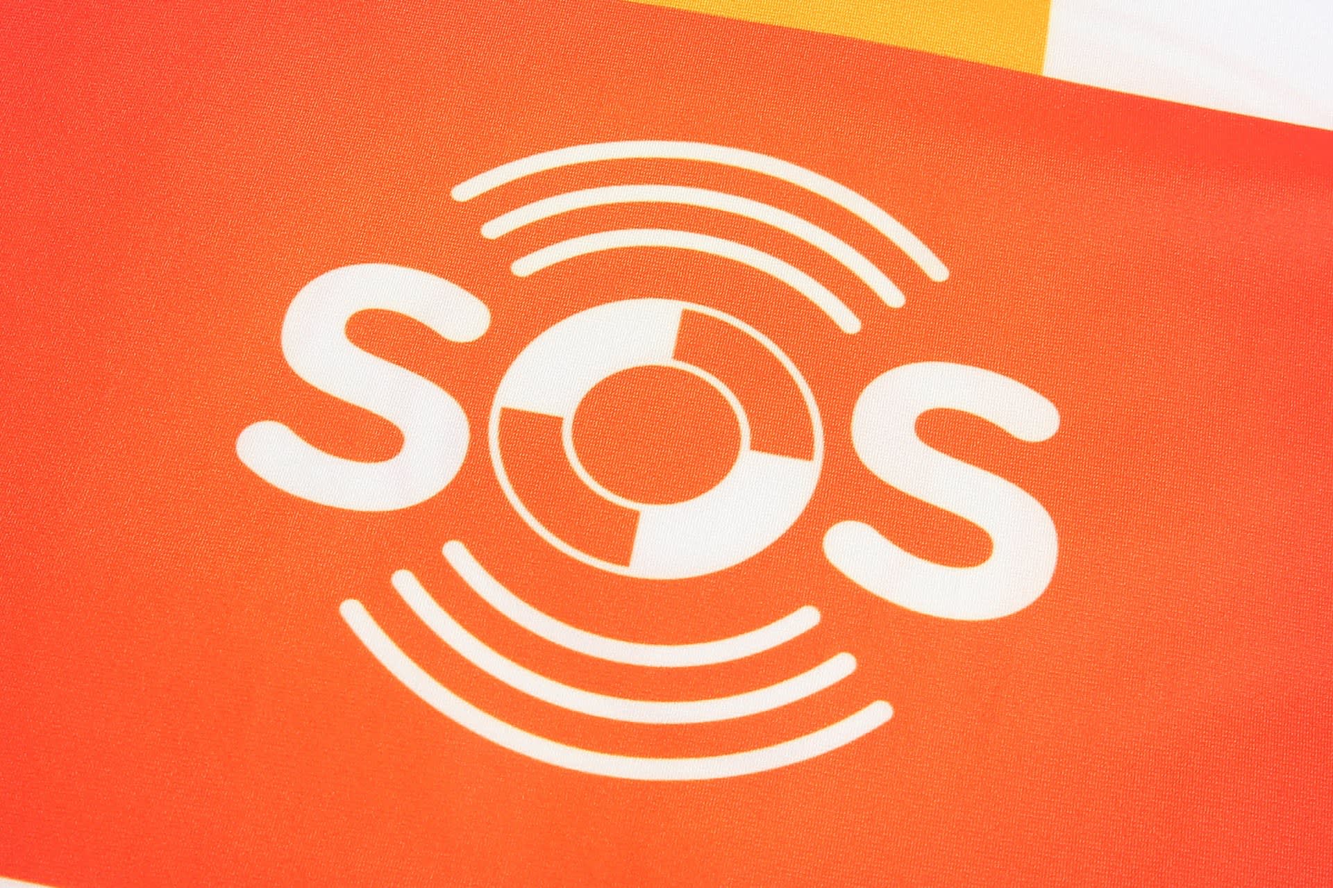 A bright orange fabric featuring a white logo consisting of the letters "SOS" and circular wave designs.