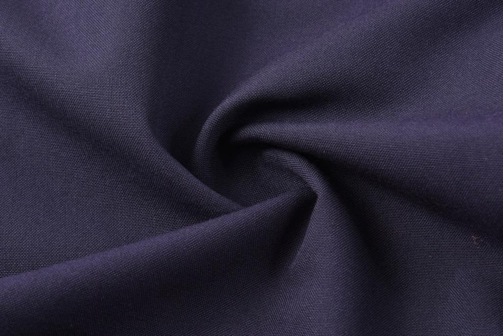 A close-up of navy fabric, showcasing a smooth texture with a slight twist. The fabric has a structured appearance.