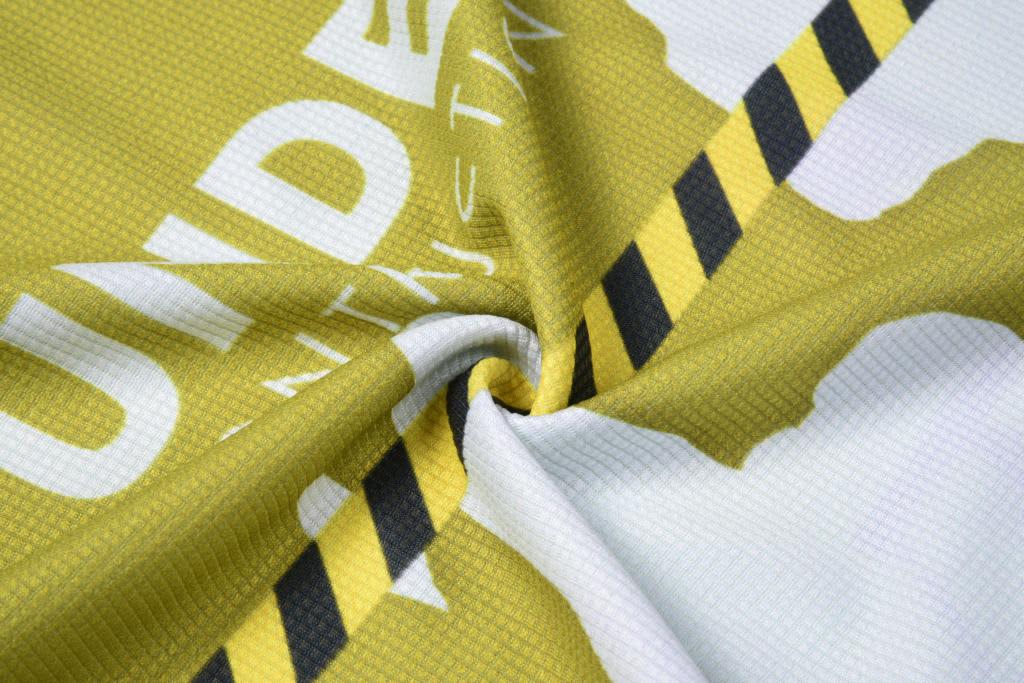 A patterned fabric featuring yellow and black stripes, with an abstract design. It has a logo present.