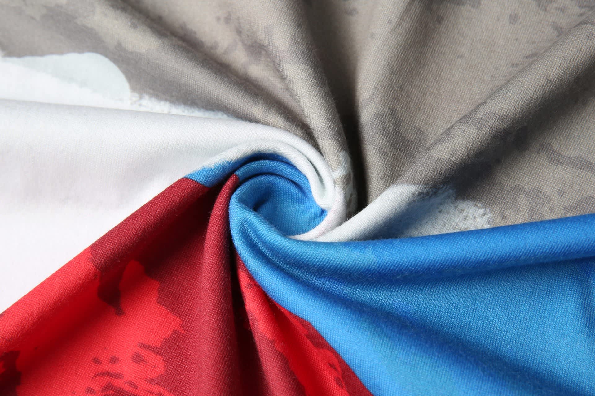 A close-up of a cotton tee fabric featuring grey, red, and blue colours with a swirling design.