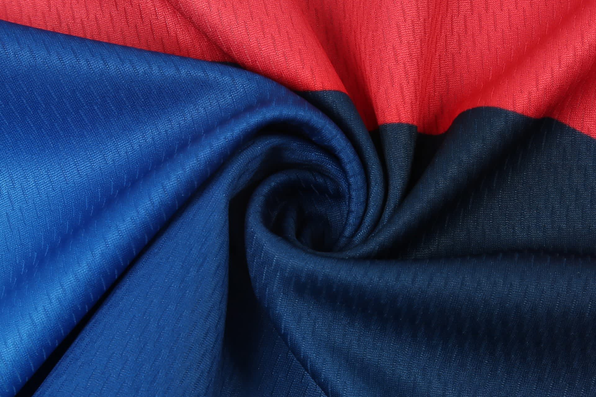 A close-up of fabric in red, blue, and black, twisted together, suitable for sports dresses. It features a textured pattern.