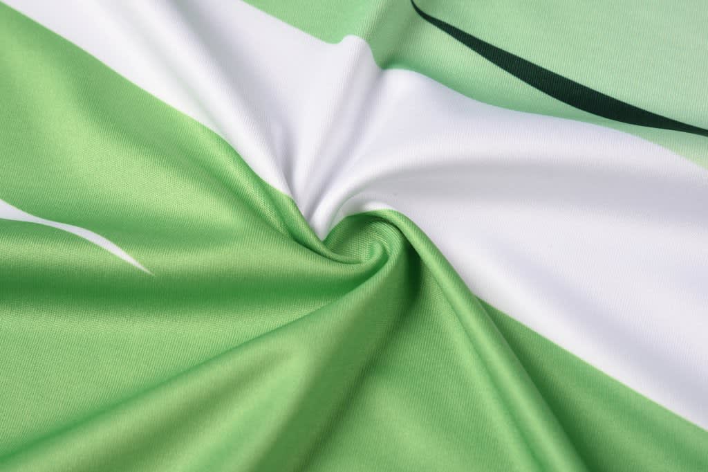A multi-sport T-shirt in green and white, featuring a smooth, textured fabric with a swirling pattern.