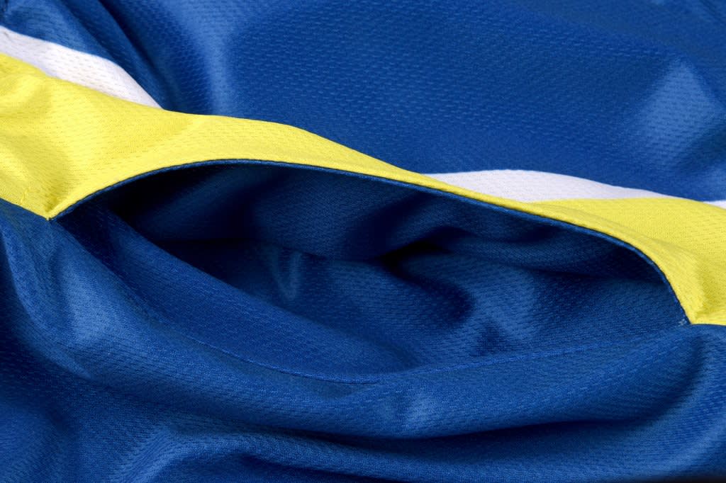 A close-up of blue fabric featuring yellow and white stripes, showcasing the texture and detail of the material.
