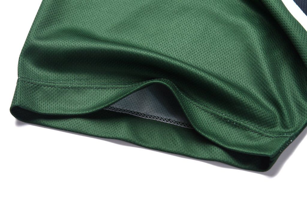 A green polo shirt in a lightweight fabric with a hem detail. It features a logo or branding.