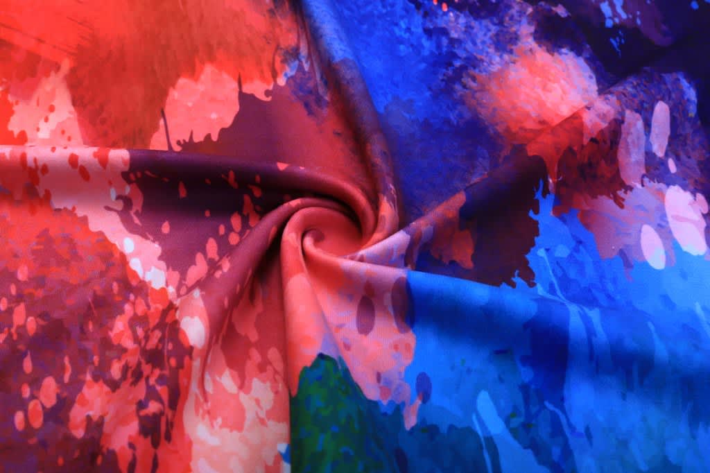 A vibrant fabric featuring a swirl of red, blue, and orange splashes, ideal for a fitness singlet.