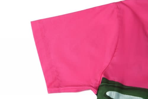 A bright pink sports jersey with a green decorative element, featuring a logo on the fabric.