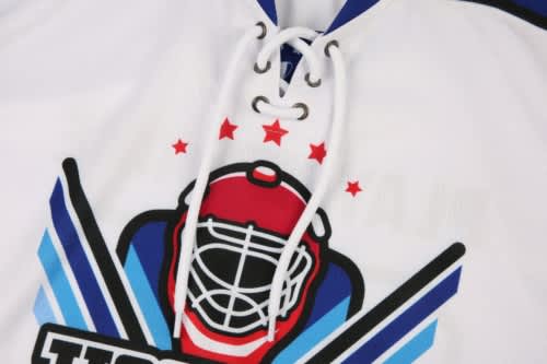 A white ice hockey jersey featuring a graphic design and a logo, with red and blue accents.