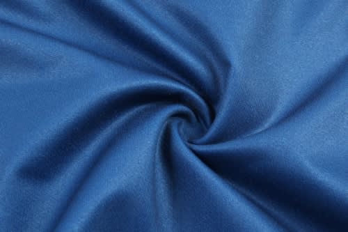 A close-up of smooth, blue fabric, showcasing a swirl pattern. The material appears shiny and lightweight.